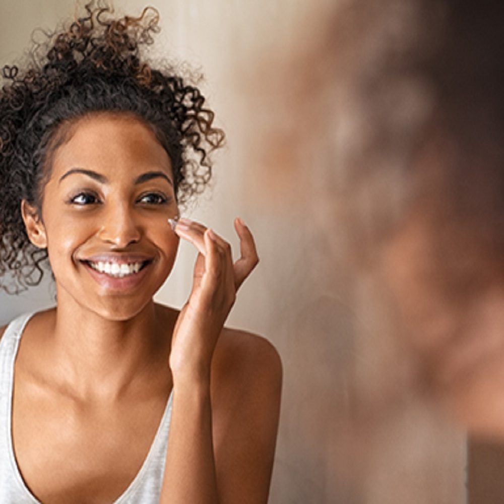 Young black woman applying skin cream